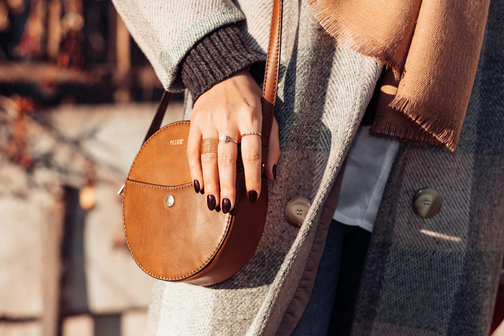 Bag, jacket, scarf worn my women with painted nails and wearing rings